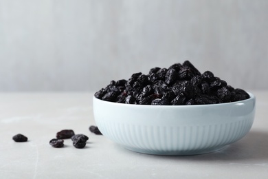 Photo of Bowl with raisins on grey table, space for text. Dried fruit as healthy snack