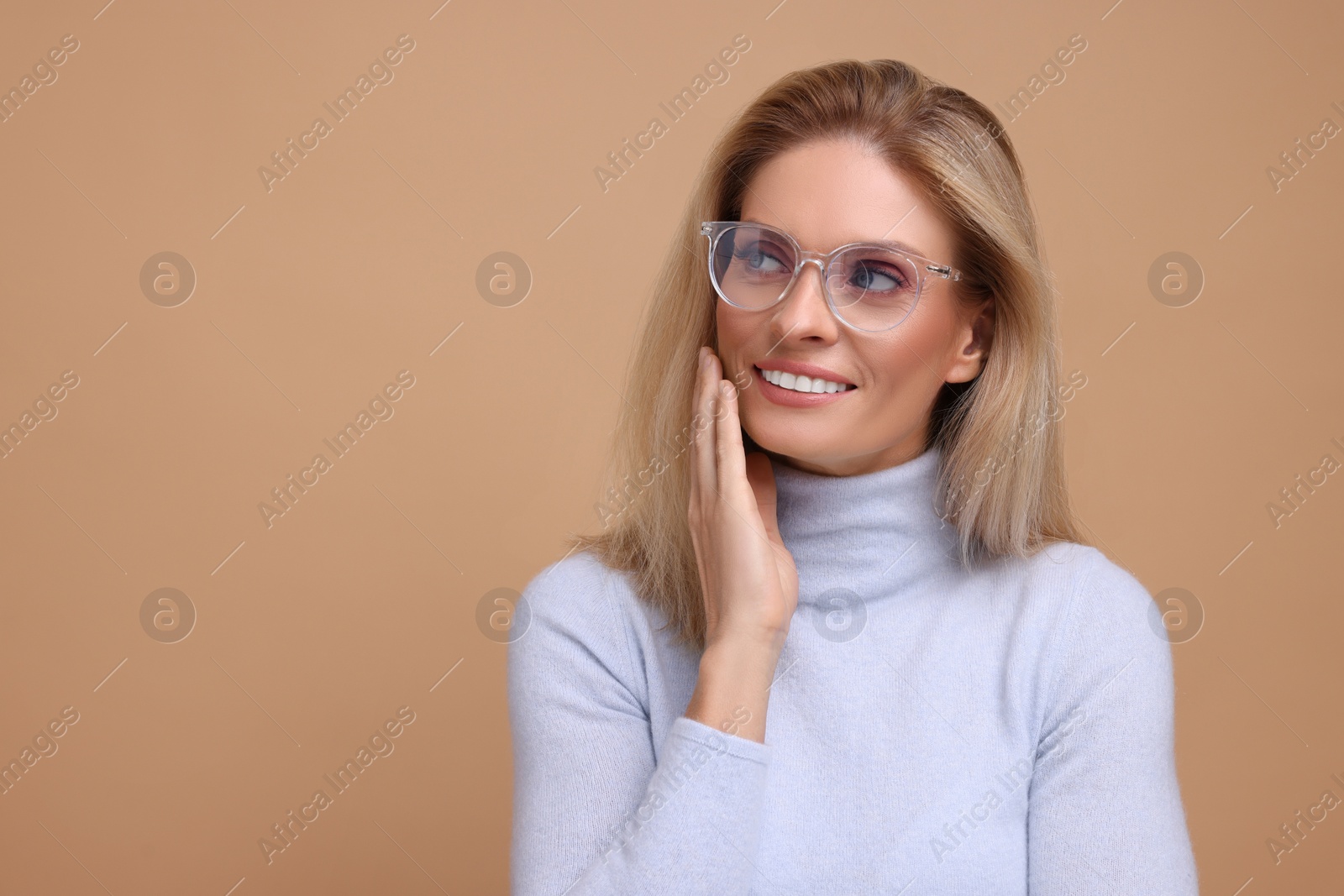 Photo of Portrait of smiling middle aged woman in glasses on beige background. Space for text