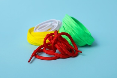 Photo of Different colorful shoe laces on light blue background