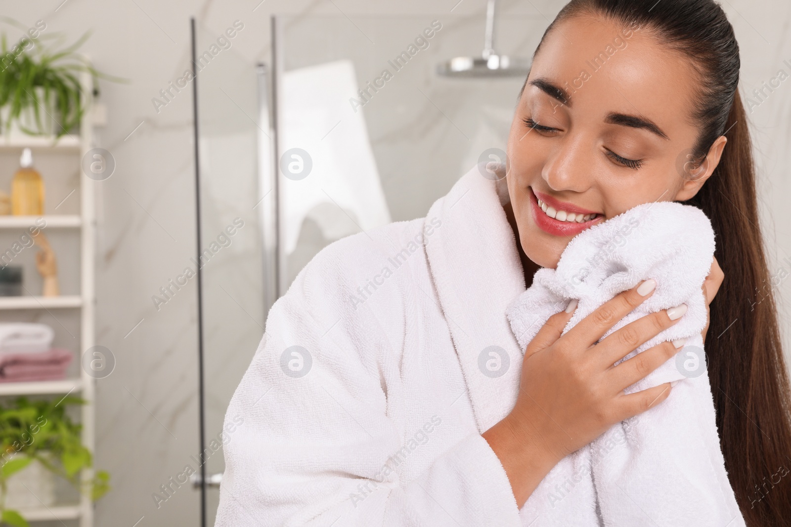 Photo of Beautiful young woman wiping face with towel in bathroom. Facial wash