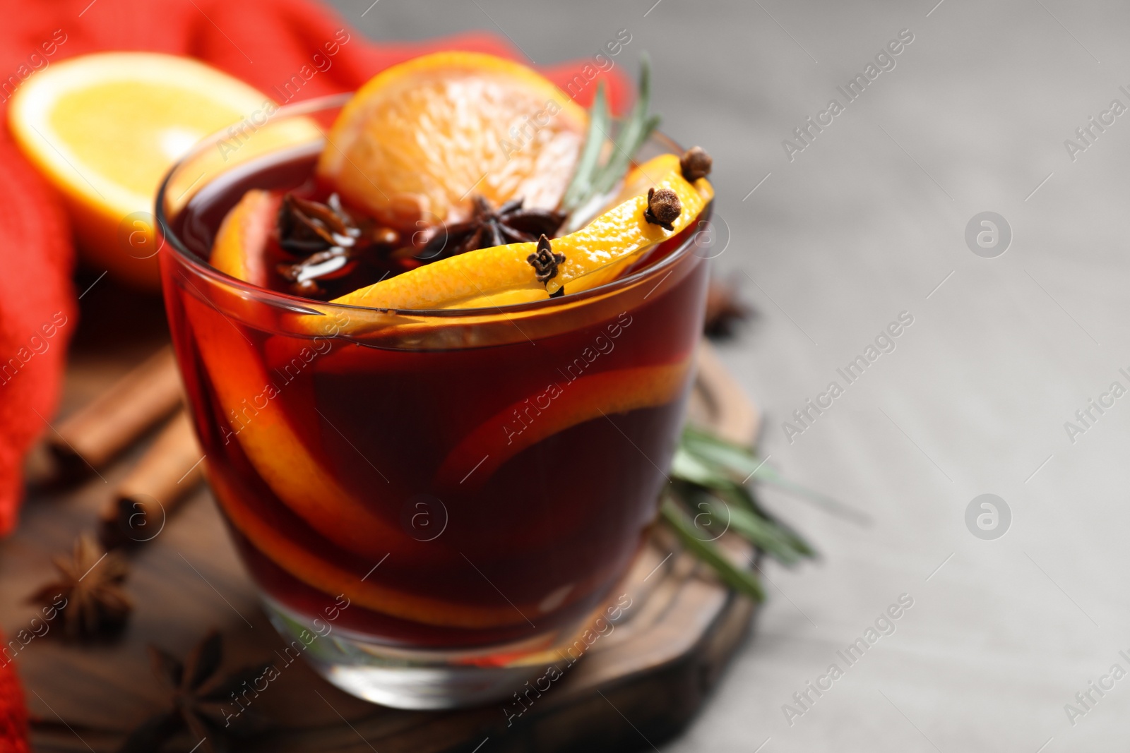 Photo of Glass with aromatic mulled wine on grey table, closeup