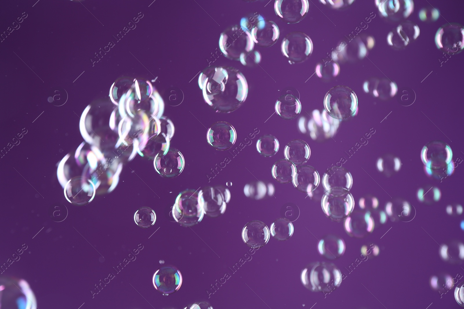 Photo of Beautiful transparent soap bubbles on purple background