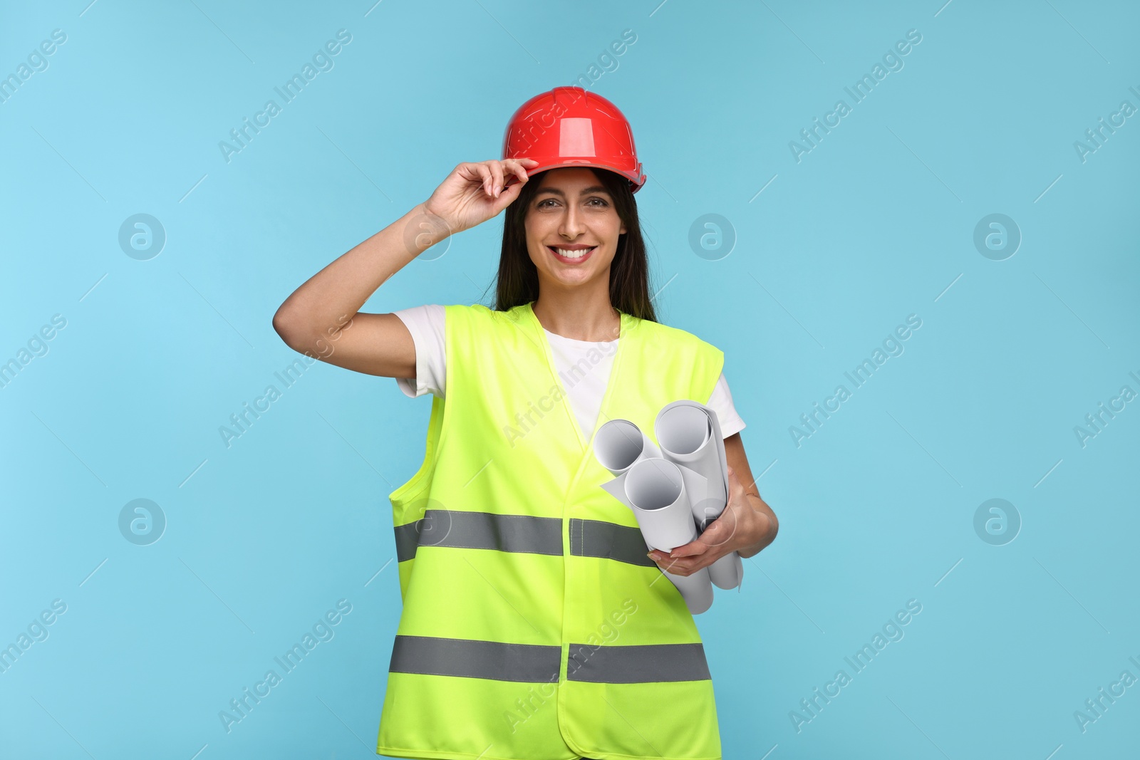 Photo of Architect in hard hat with drafts on light blue background