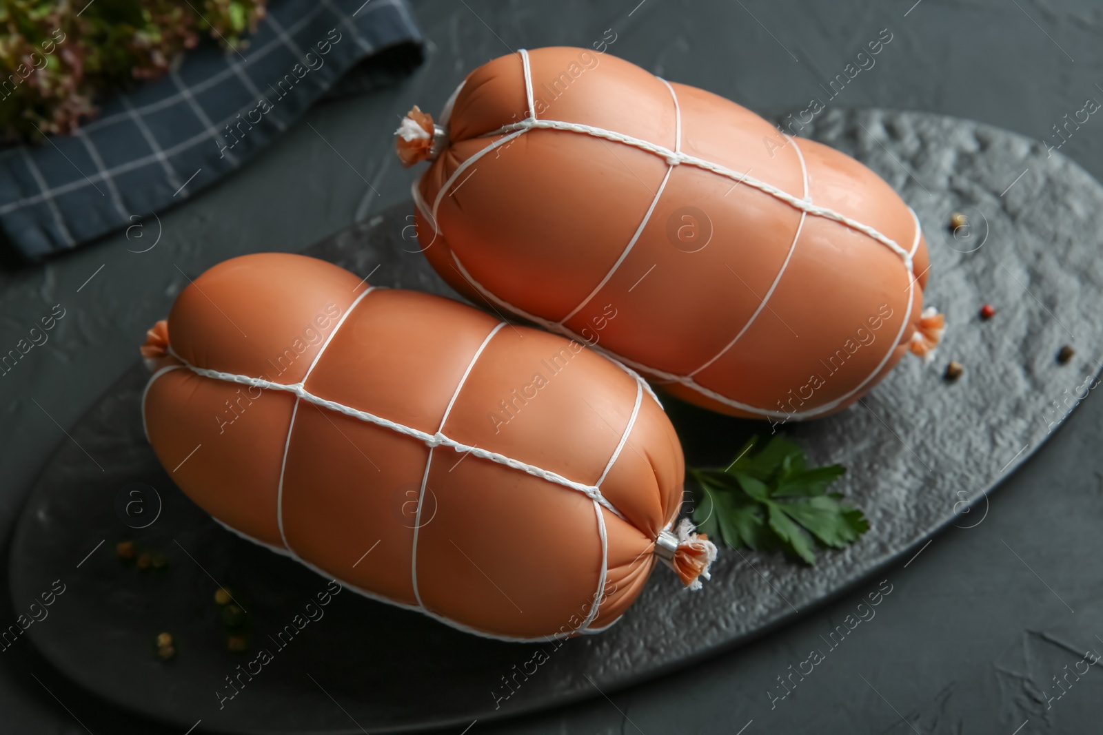 Photo of Tasty boiled sausages on dark textured table, closeup