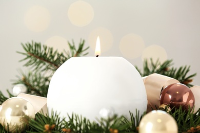 Burning white candle with Christmas decor on blurred background