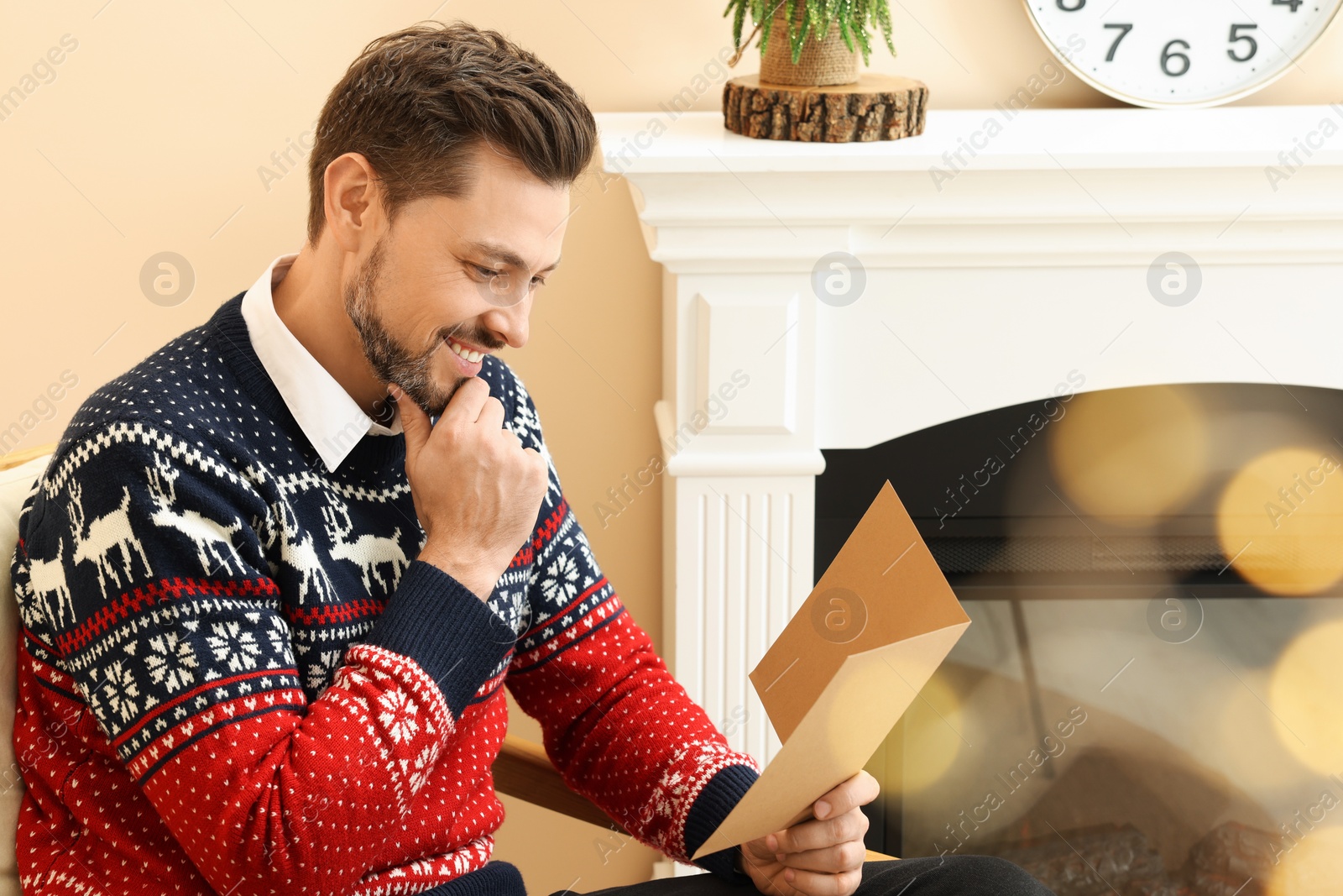 Photo of Happy man reading Christmas greeting card in living room