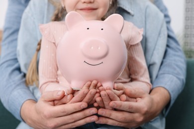 Photo of Family budget. Little girl and her parents with piggy bank, closeup