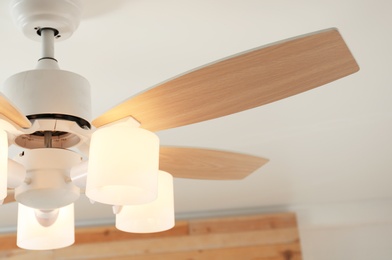 Photo of Modern ceiling fan with lamps indoors, closeup. Interior element