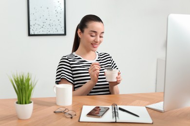 Photo of Happy woman with tasty yogurt in office