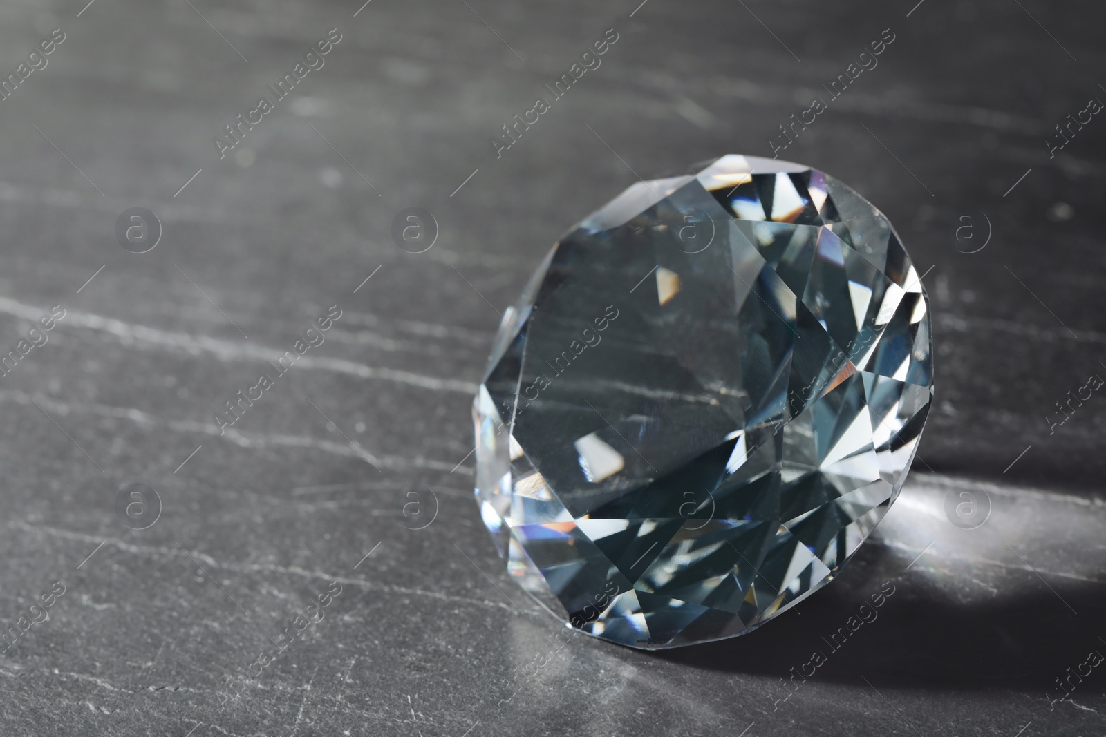 Photo of Beautiful dazzling diamond on black textured background, closeup. Space for text