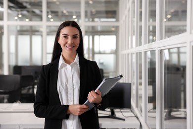 Happy woman with folder in office, space for text. Lawyer, businesswoman, accountant or manager