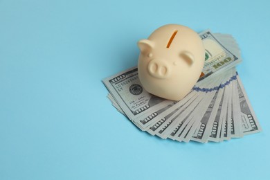 Photo of Money exchange. Dollar banknotes and piggy bank on light blue background, space for text