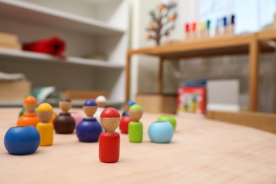 Photo of wooden colorful dolls shaped building blocks on table in room. Montessori toy