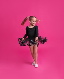 Cute little girl in black dress dancing on pink background