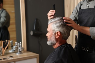 Hair styling. Professional hairdresser working with client in barbershop, closeup