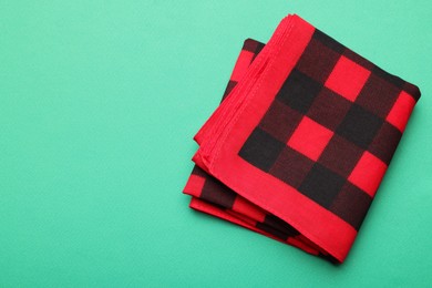 Photo of Folded red checkered bandana on turquoise background, top view. Space for text