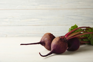 Photo of Fresh beets on wooden table against white background. Space for text