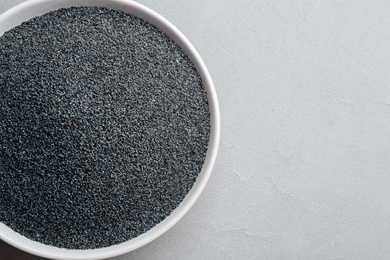 Photo of Poppy seeds in bowl on grey table, top view. Space for text