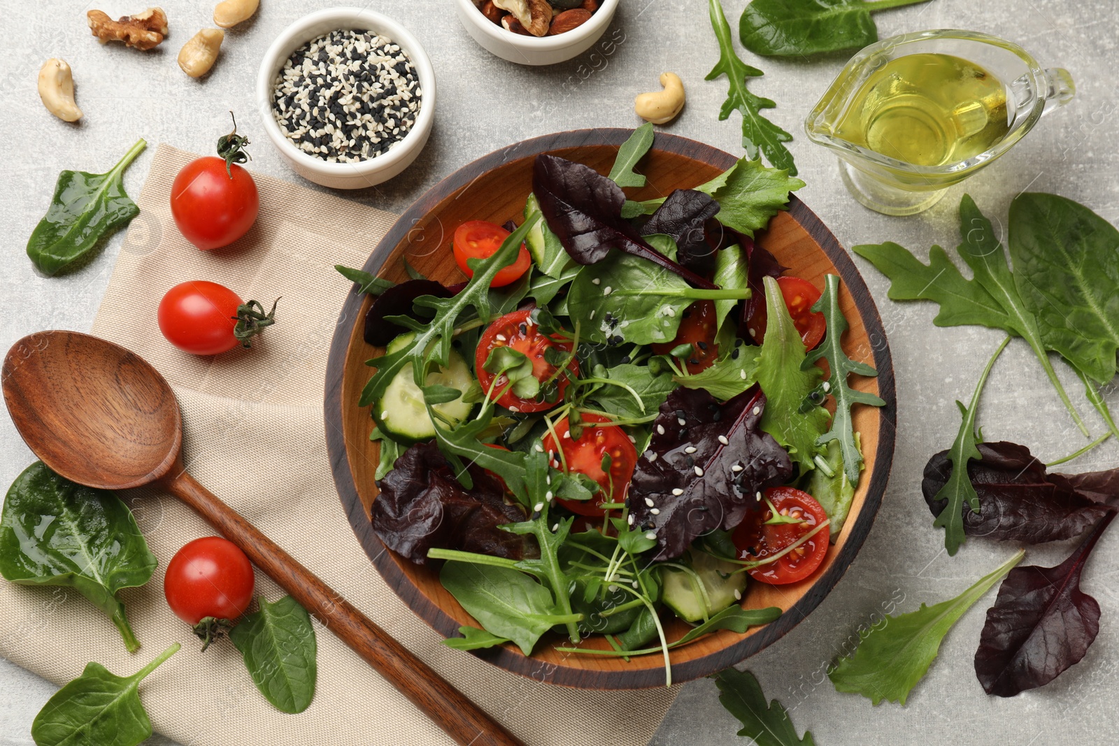 Photo of Tasty fresh vegetarian salad and ingredients on grey table, flat lay