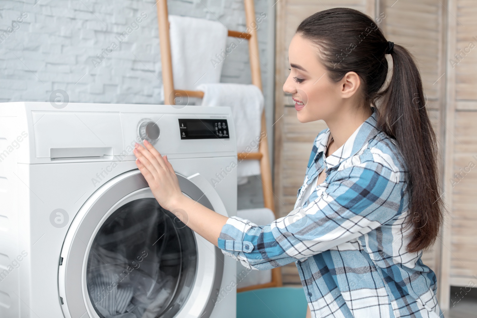 Photo of Young woman doing laundry at home