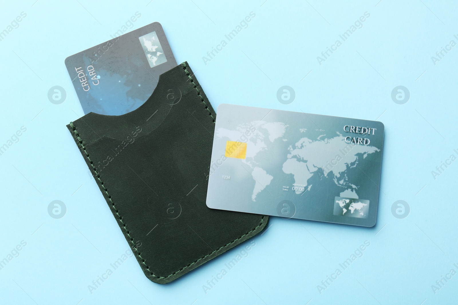 Photo of Leather card holder with credit cards on light blue background, top view