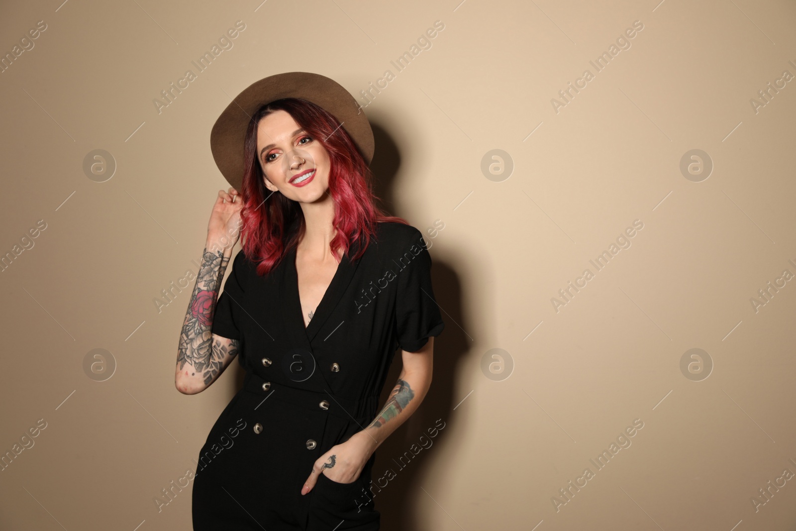 Photo of Beautiful woman with tattoos on arms against beige background. Space for text