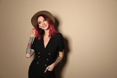 Photo of Beautiful woman with tattoos on arms against beige background. Space for text