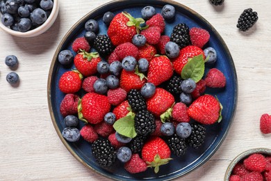 Different fresh ripe berries on light wooden table, flat lay