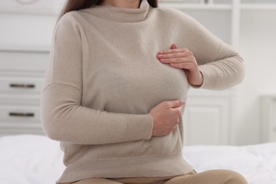 Photo of Mammology. Woman doing breast self-examination in bedroom, closeup