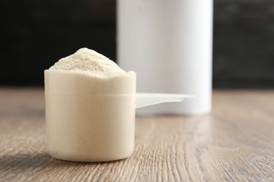 Photo of Scoop of protein powder on wooden table