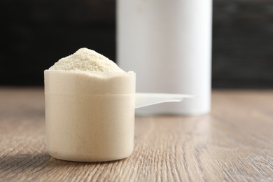 Scoop of protein powder on wooden table