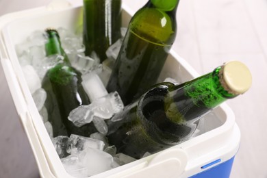 Plastic cool box with ice cubes and beer, closeup