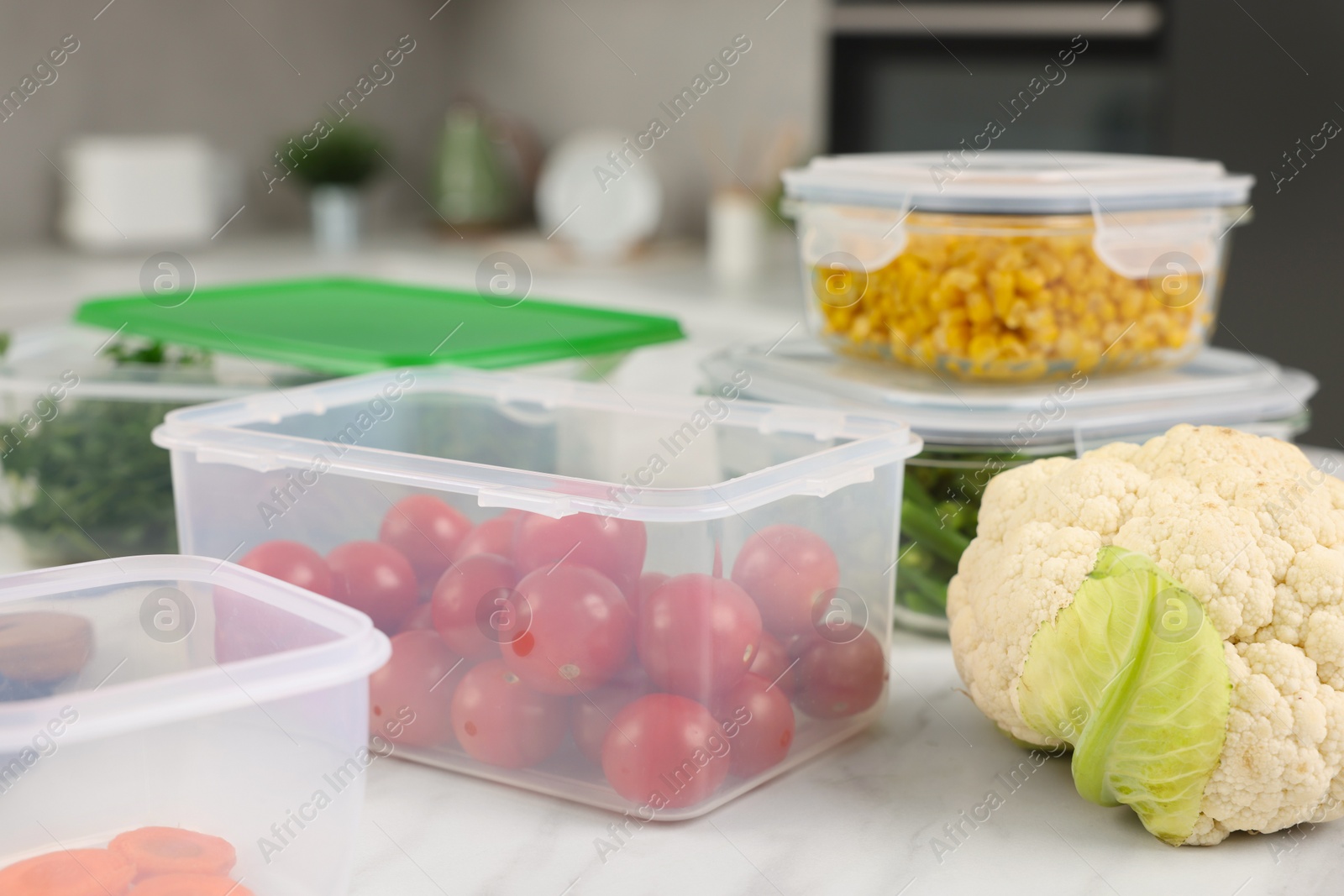 Photo of Containers with fresh products on white marble table in kitchen. Food storage