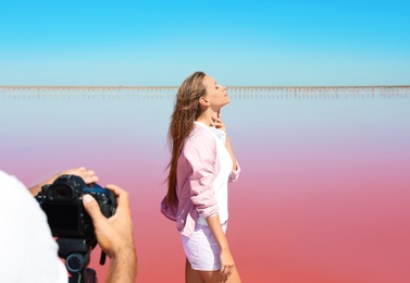 Professional photographer taking photo of woman near pink lake on sunny day