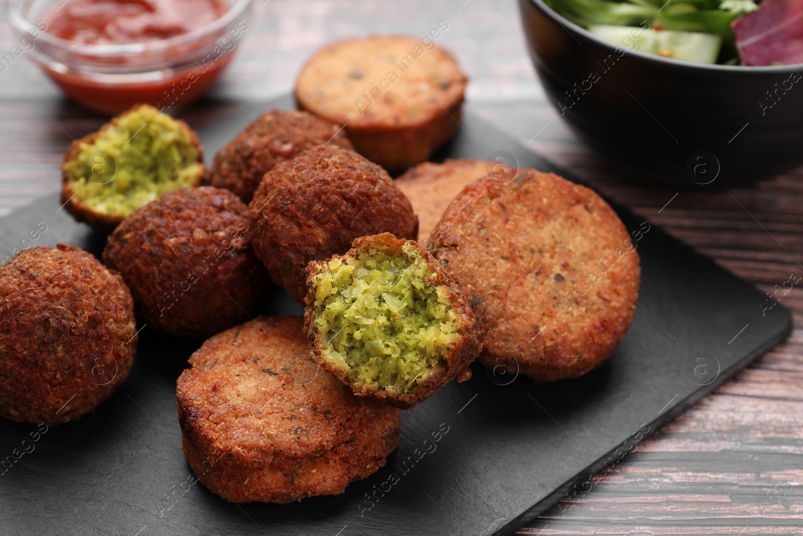 Photo of Delicious vegan cutlets and falafel balls on wooden table, closeup