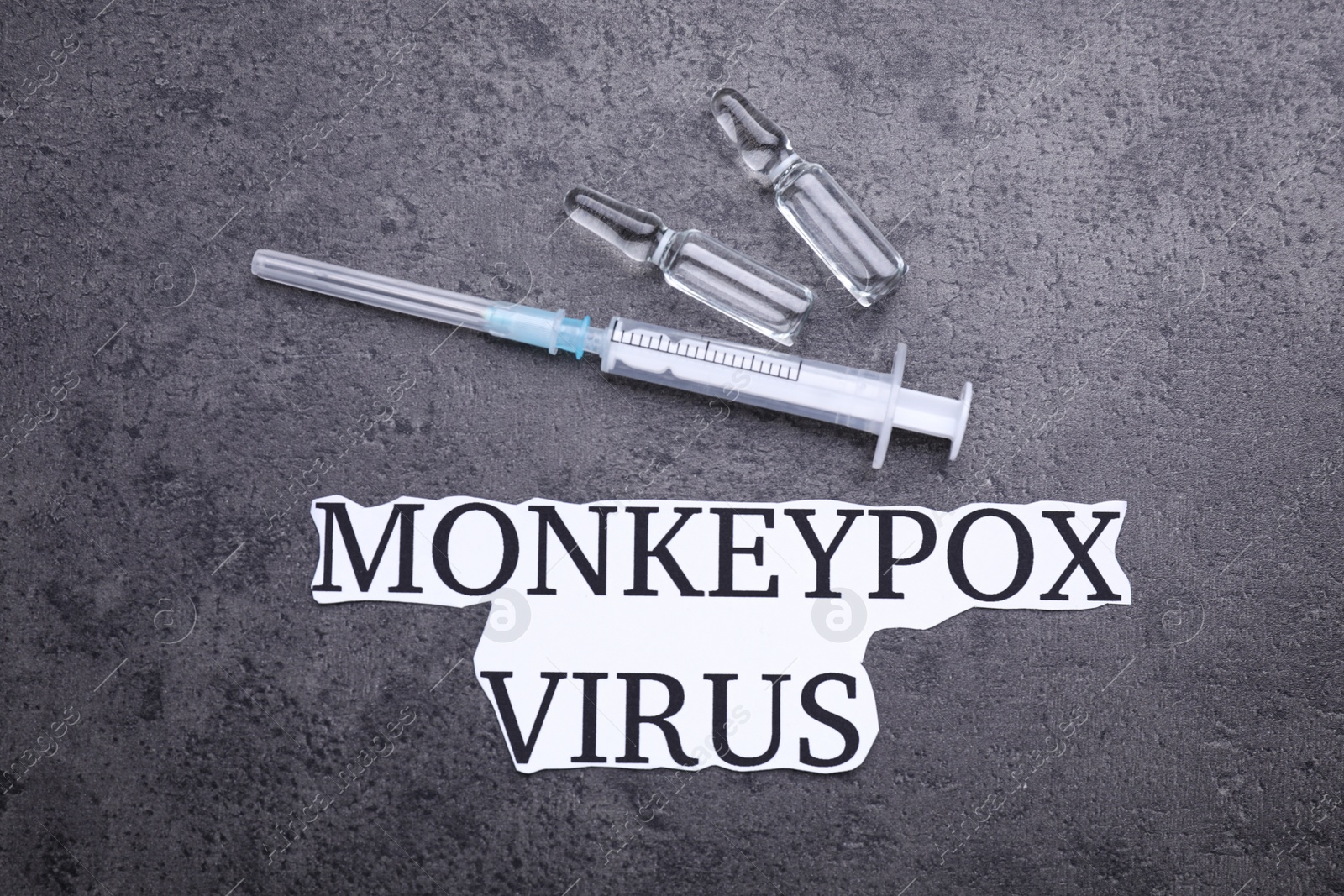 Photo of Words Monkeypox Virus, syringe and vials on grey table, flat lay