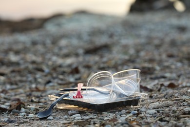 Photo of Used plastic tableware at beach, closeup and space for text. Environmental pollution concept