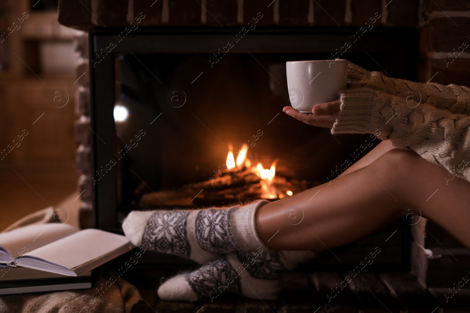 Photo of Woman with cup of hot cocoa near fireplace indoors, closeup