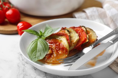 Delicious ratatouille served with basil on white marble table, closeup