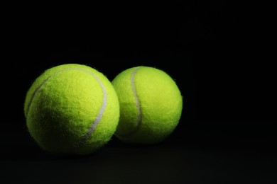 Photo of Two tennis balls on black background, closeup. Space for text