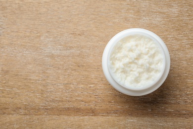 Jar of shea butter and space for text on wooden background, top view