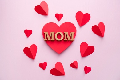 Beautiful composition with word MOM and paper hearts on color background. Happy Mother's Day