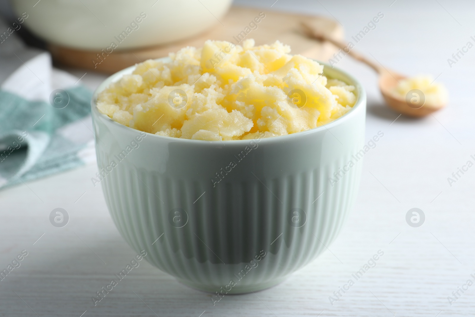 Photo of Bowl of Ghee butter on white wooden table, closeup