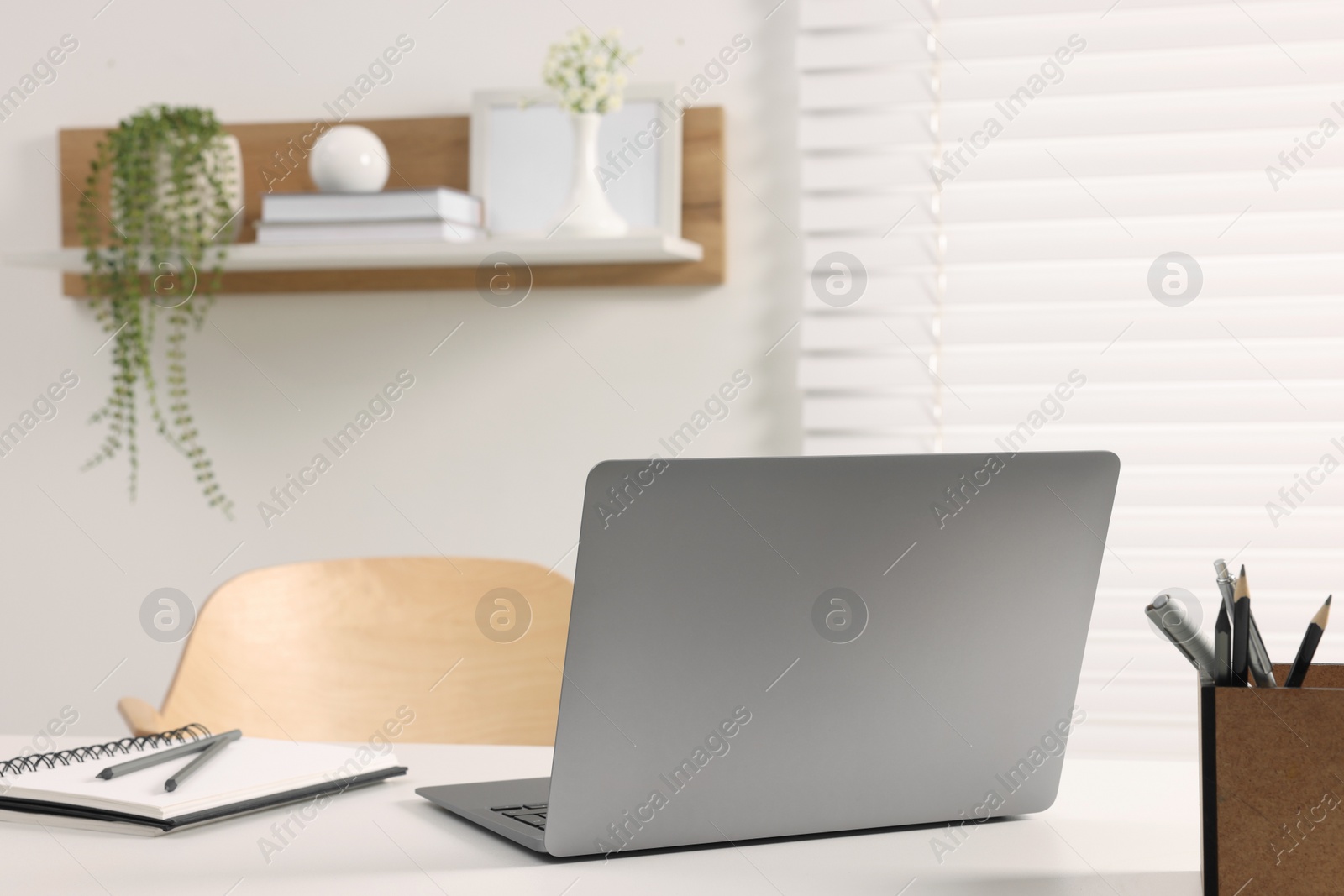 Photo of Home office. Laptop and stationery on white desk indoors. Space for text