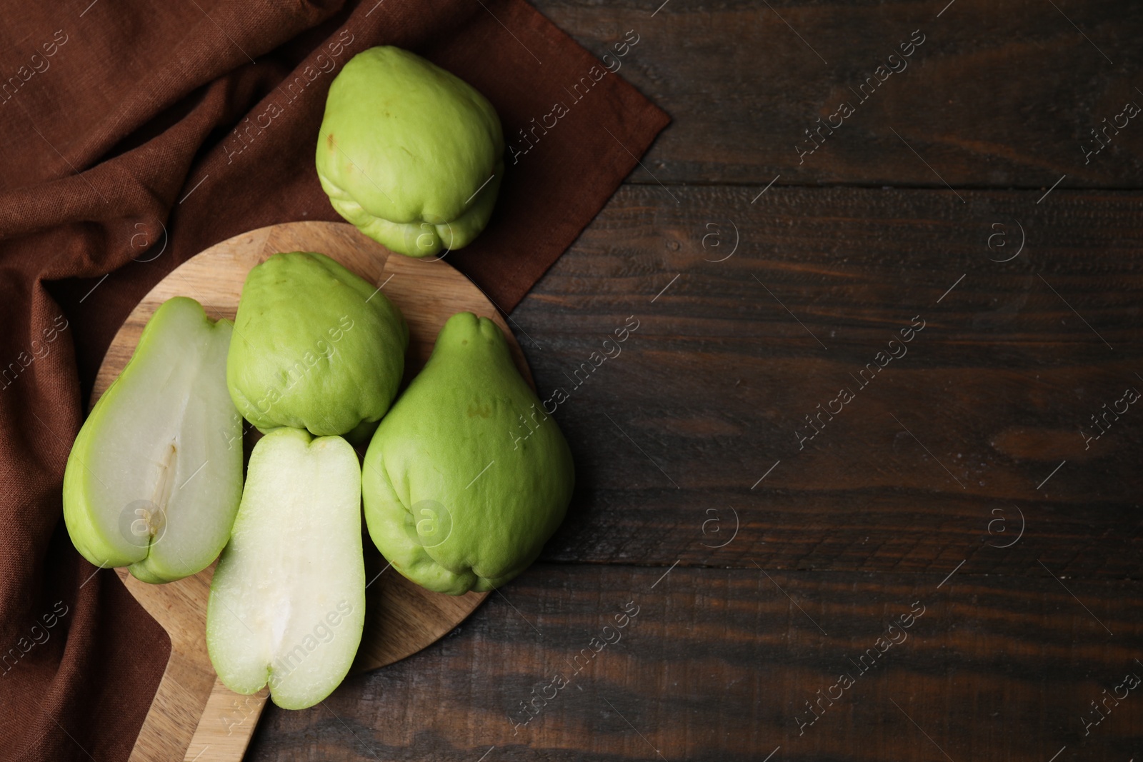 Photo of Cut and whole chayote on wooden table, flat lay. Space for text