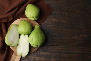 Cut and whole chayote on wooden table, flat lay. Space for text