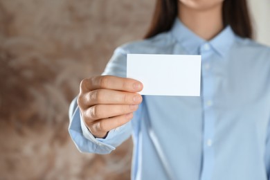 Photo of Woman holding blank business card on blurred background, closeup. Mockup for design
