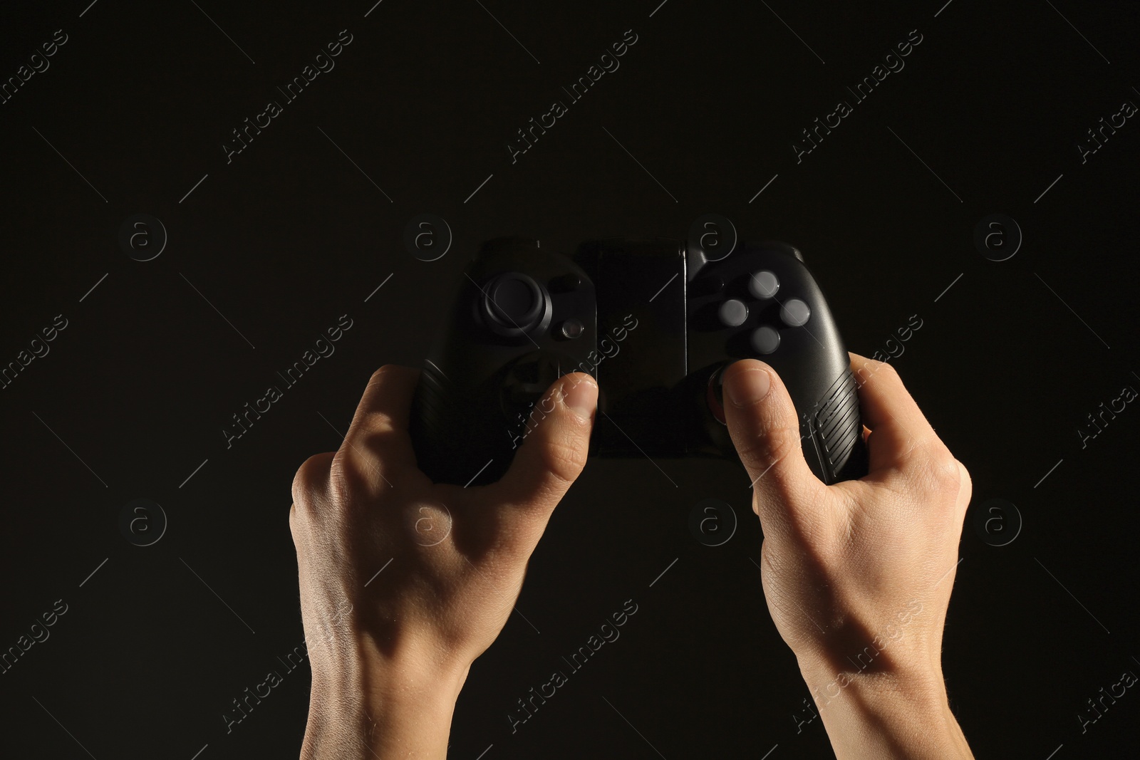 Photo of Man holding video game controller on black background, closeup