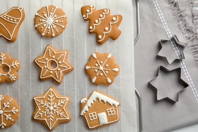 Photo of Tasty decorated Christmas cookies on baking parchment, top view