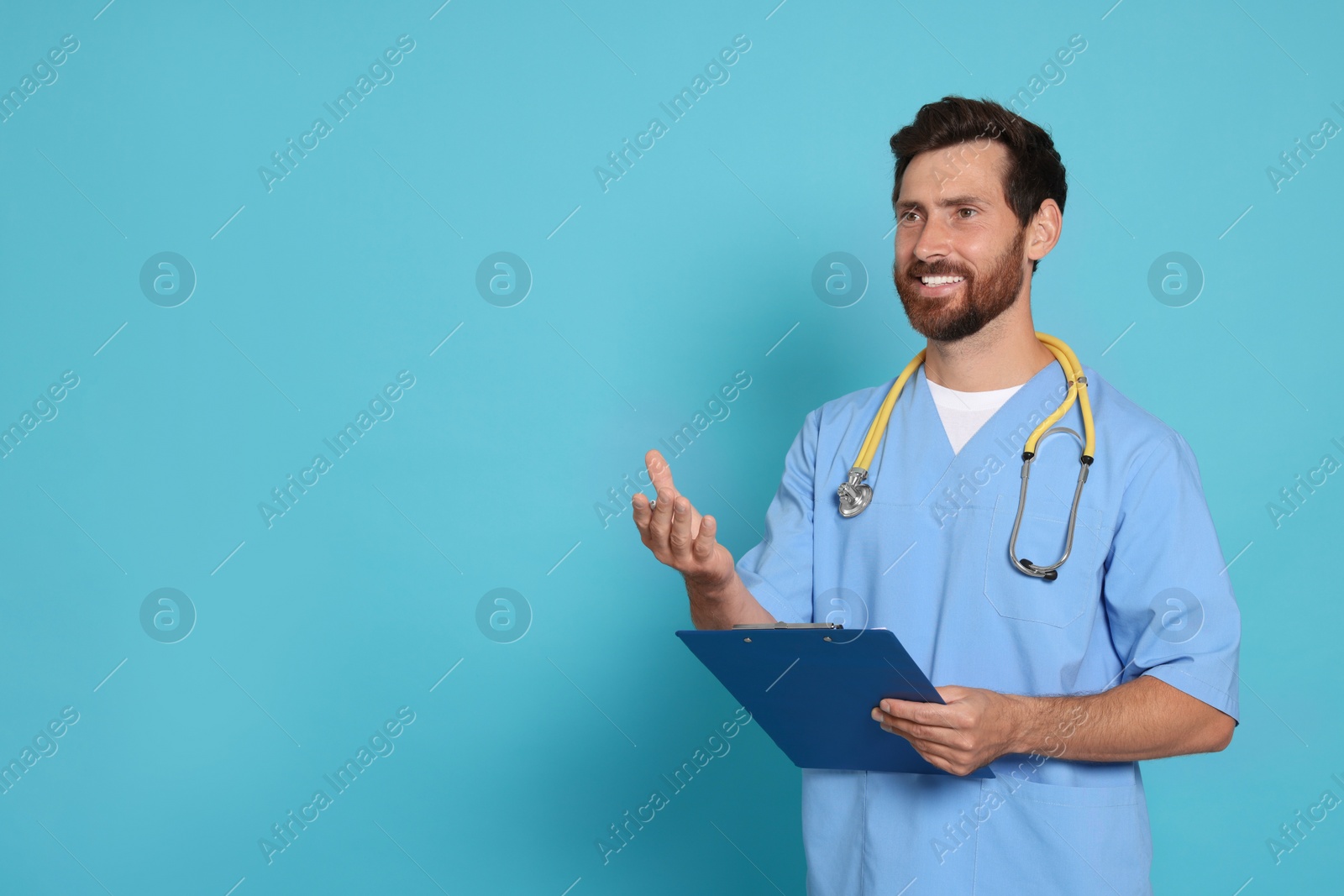 Photo of Happy doctor with stethoscope and clipboard on light blue background. Space for text